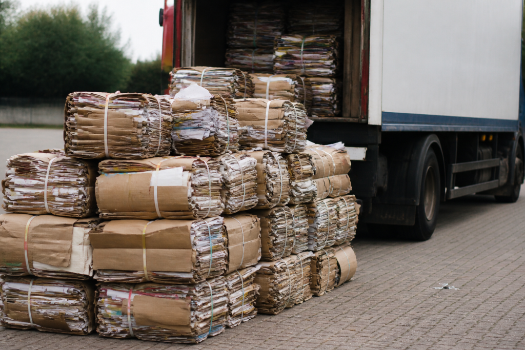Gebundelde stapels oud papier naast een vrachtwagen