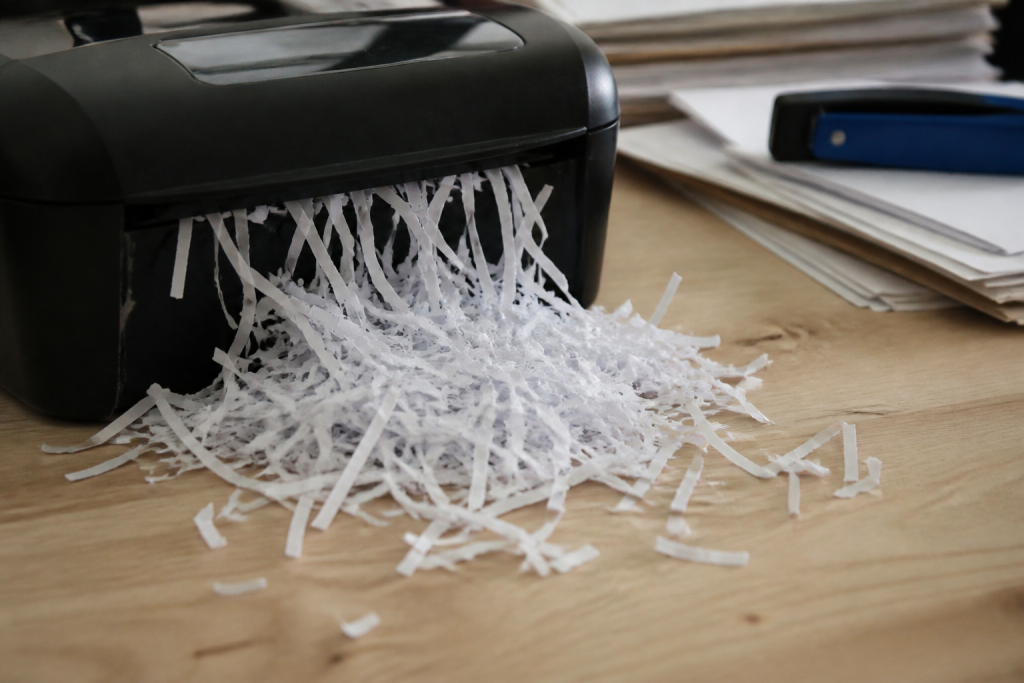 Papierversnipperaar spuugt witte strookjes uit op houten bureau